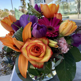 Colorful bouquet of roses, tulips, and a gerbera daisy in a glass vase