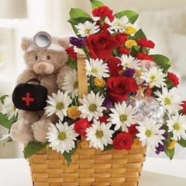 Basket arrangement with red roses, daisies, and a teddy bear holding a medical bag