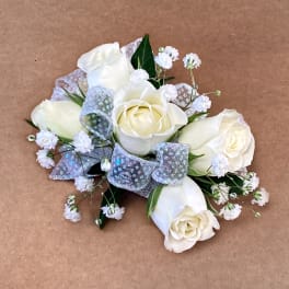 White rose bouquet with silver ribbon accents on a brown background