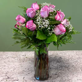 Tall glass vase of pink roses with white filler flowers