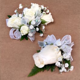 White rose corsages with baby's breath and silver ribbon