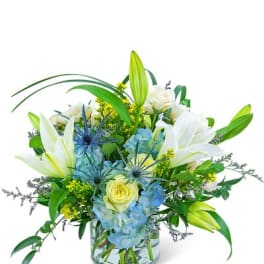 White lilies and blue hydrangeas in a glass vase