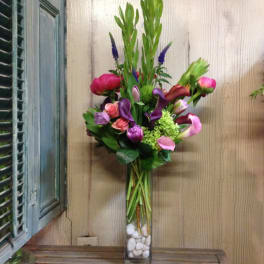 Mixed bouquet in a tall glass vase with pink, purple, and green flowers