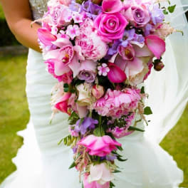 Bride holding a cascading bouquet of pink and purple flowers