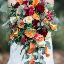 Bridal bouquet with orange calla lilies, red roses, and trailing eucalyptus