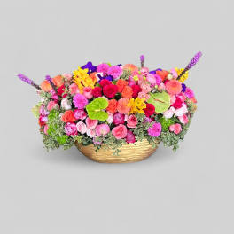 Colorful mixed flower arrangement in a low gold basket