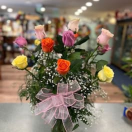Mixed roses in a glass vase with a pink ribbon bow