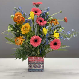 Colorful mixed bouquet in a patterned square vase