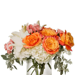 Bouquet of orange and pink roses with white lilies in a glass vase