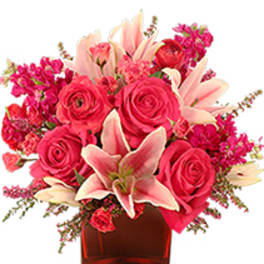 Pink roses and lilies arranged in a red glass vase