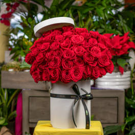 Red roses arranged in a white hat box with a black ribbon