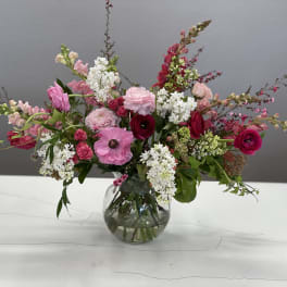 Pink and white mixed flower arrangement in a round glass vase