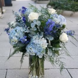 Blue and white floral arrangement in a clear glass vase