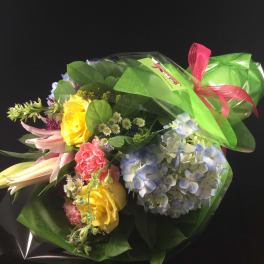 Wrapped bouquet of yellow roses, blue hydrangea, and pink lilies