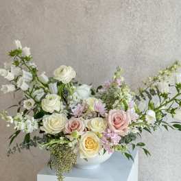 Pastel bouquet of roses and white blooms in a white bowl vase