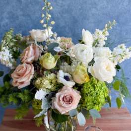 Mixed bouquet of pale roses and white blooms in a glass vase