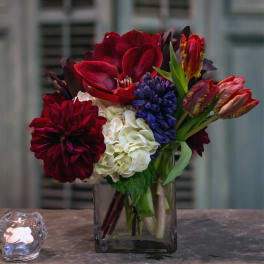 Mixed bouquet of red, white, and purple flowers in a glass vase