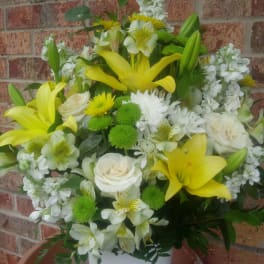 Yellow lilies and white roses arranged in a white vase