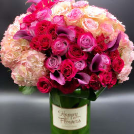 Pink and cream roses with purple calla lilies in a green vase
