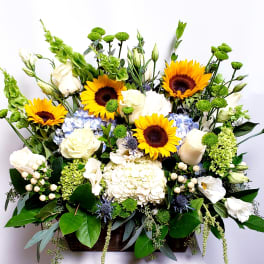 Mixed bouquet with sunflowers, white roses, and blue hydrangeas in a rectangular container
