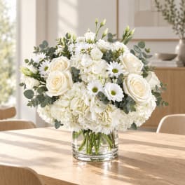 White roses and daisies arranged in a clear glass vase