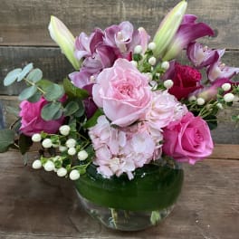 Pink and purple bouquet in a glass vase with roses and lilies