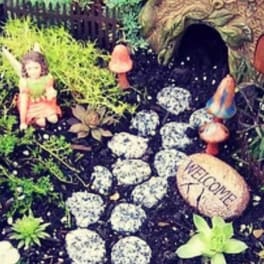 Miniature fairy garden with a tiny house, stepping stones, and small figurines