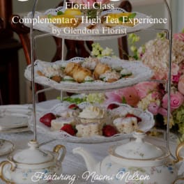 Tiered serving stand with pastries and flowers on a tea table