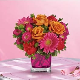 Pink and orange mixed bouquet in a magenta glass vase