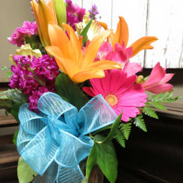 Bright mixed bouquet with orange lilies, pink gerbera daisies, and a blue ribbon