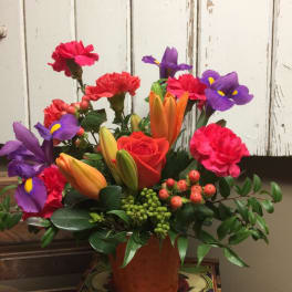 Colorful bouquet with roses, lilies, irises, and carnations in a copper vase