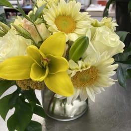 Yellow orchids, white roses, and pale daisies in a glass vase