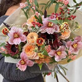 Handheld bouquet of pink and peach flowers wrapped in paper
