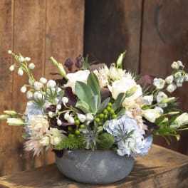 Mixed floral arrangement in a gray bowl vase with white and pale blue blooms