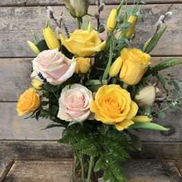 Yellow and pale pink roses arranged in a glass vase