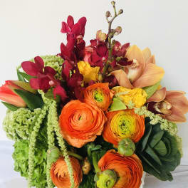 Bright bouquet of orange ranunculus and orchids in a vase