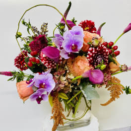 Colorful bouquet with orchids, calla lilies, roses, and dahlias in a glass vase