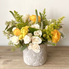 Yellow and white roses arranged in a patterned ceramic vase