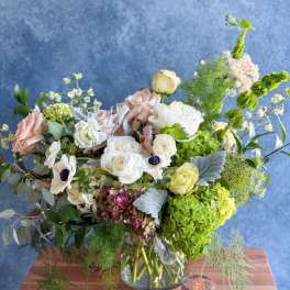 Mixed pastel bouquet in a glass vase with white, pink, and green blooms