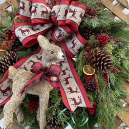 Christmas wreath with plaid ribbon, pinecones, and straw deer ornaments