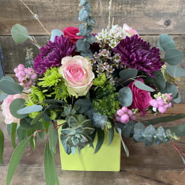 Mixed bouquet with pink and purple flowers in a lime green box