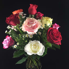 Mixed roses in a clear glass vase with small white filler flowers