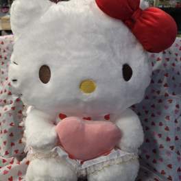 Hello Kitty plush holding a pink heart pillow