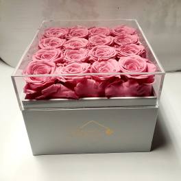 Pink roses arranged in a clear square box on a gray base
