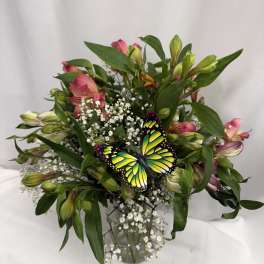 Bouquet of pink alstroemeria with baby's breath and a butterfly pick in a glass vase