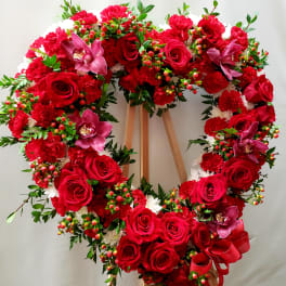 Heart-shaped wreath of red roses and carnations with pink orchids