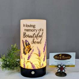 Memorial candle with butterfly and lavender design beside a small card holder