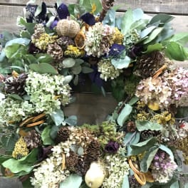 Large wreath with dried flowers, pinecones, and eucalyptus on a wooden background