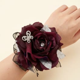 Dark burgundy rose wrist corsage with silver accents on a wrist