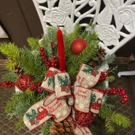 Christmas arrangement with pine, red berries, and a red candle